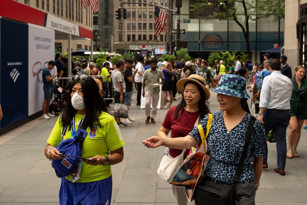 A volunteer for the World Cup wears a mask as smoke from wildfires blankets the sky at the...