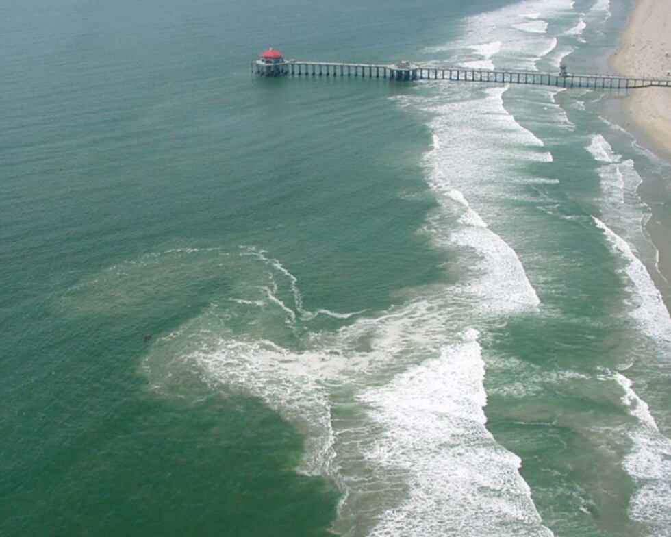 A look at a stream of discolored water near a pier showing a rip current. (Source NOAA)