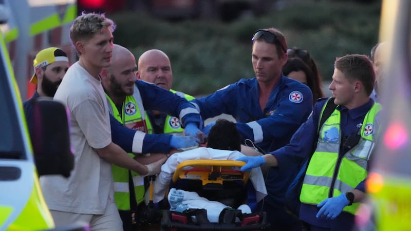 Emergency workers transport a person on a stretcher after a reported shooting at Bondi Beach,...
